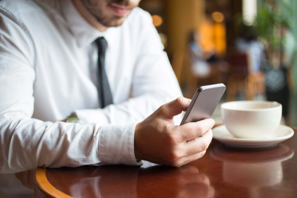 Man on smartphone in cafe with focus on smartphone watching video content